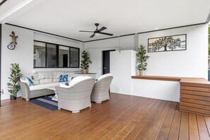 A modern living room with a sofa, two wicker chairs, a wooden coffee table, and a ceiling fan. - Elk Estate (Inverloch)