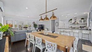 A modern kitchen with white cabinets, a stainless steel range hood, and a built-in oven. - Elk Estate (Inverloch)