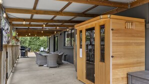 A covered patio area with a dining table and chairs, a sauna, and a grill. - Elk Estate (Inverloch)