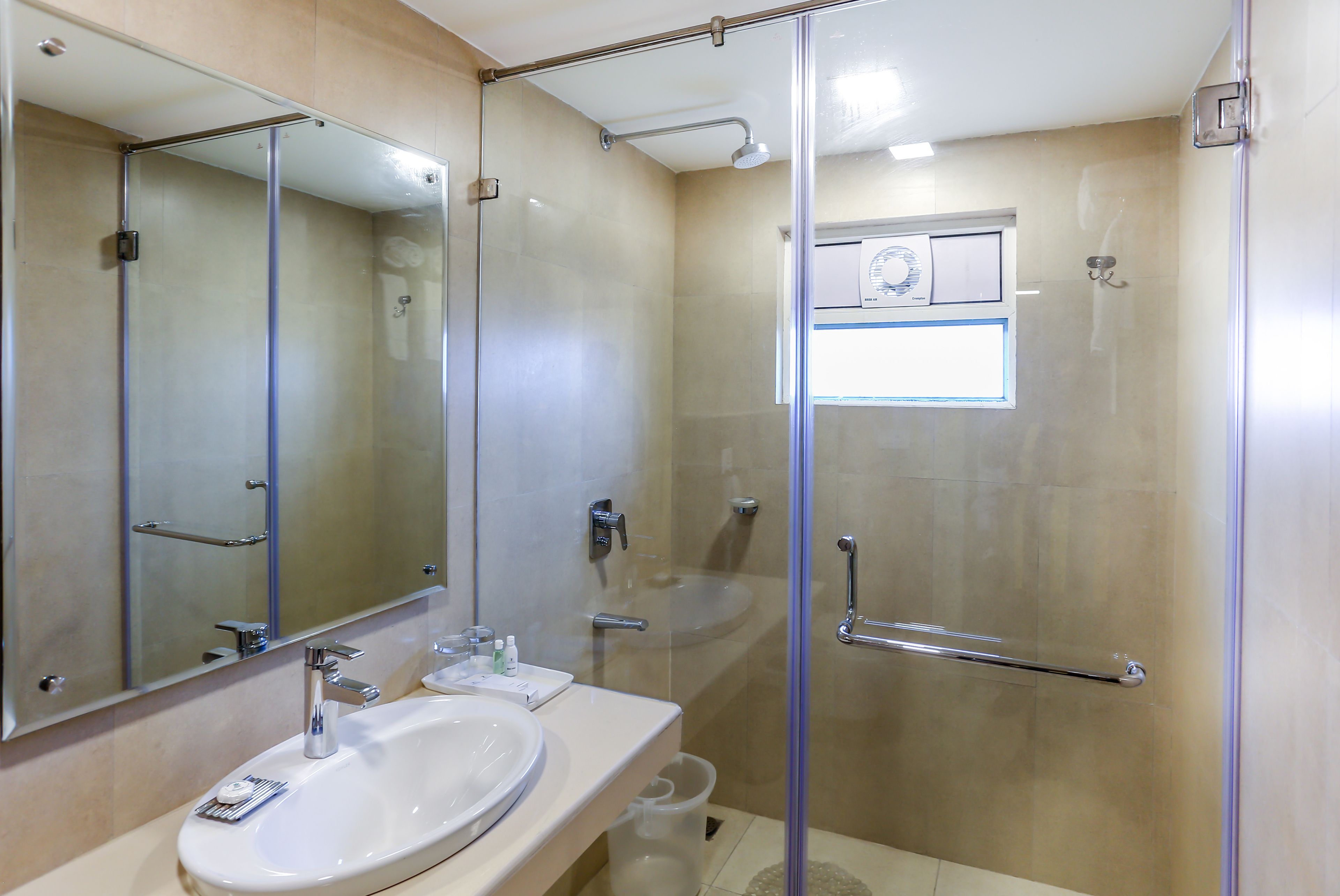 Ein modernes Badezimmer mit einer Duschkabine aus Glas, einem großen Spiegel und einem weißen Waschbecken.