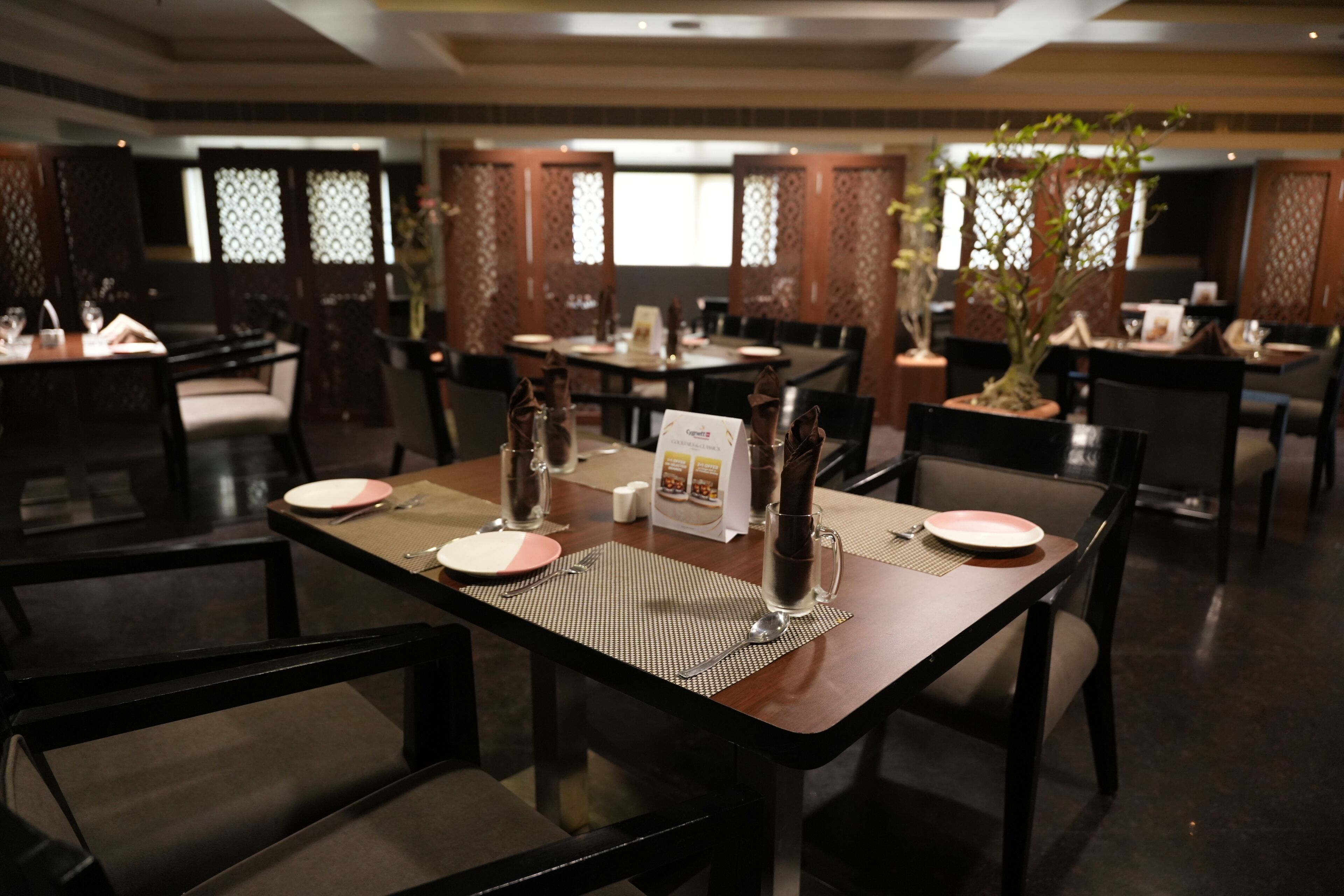 A restaurant with multiple dining tables, each set with plates, cutlery, and water glasses.