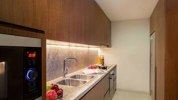 A modern kitchen with a built-in microwave, stainless steel sink, and wooden cabinets.