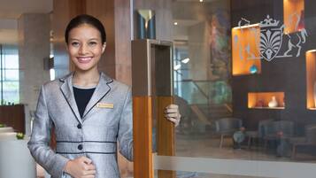 A person standing in a lobby with a modern interior design, including a large wooden column and a glass partition.