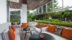 An outdoor seating area with a modern design, featuring a mix of sofas and tables, and a view of greenery. - Ascott Sudirman Jakarta (Jakarta)