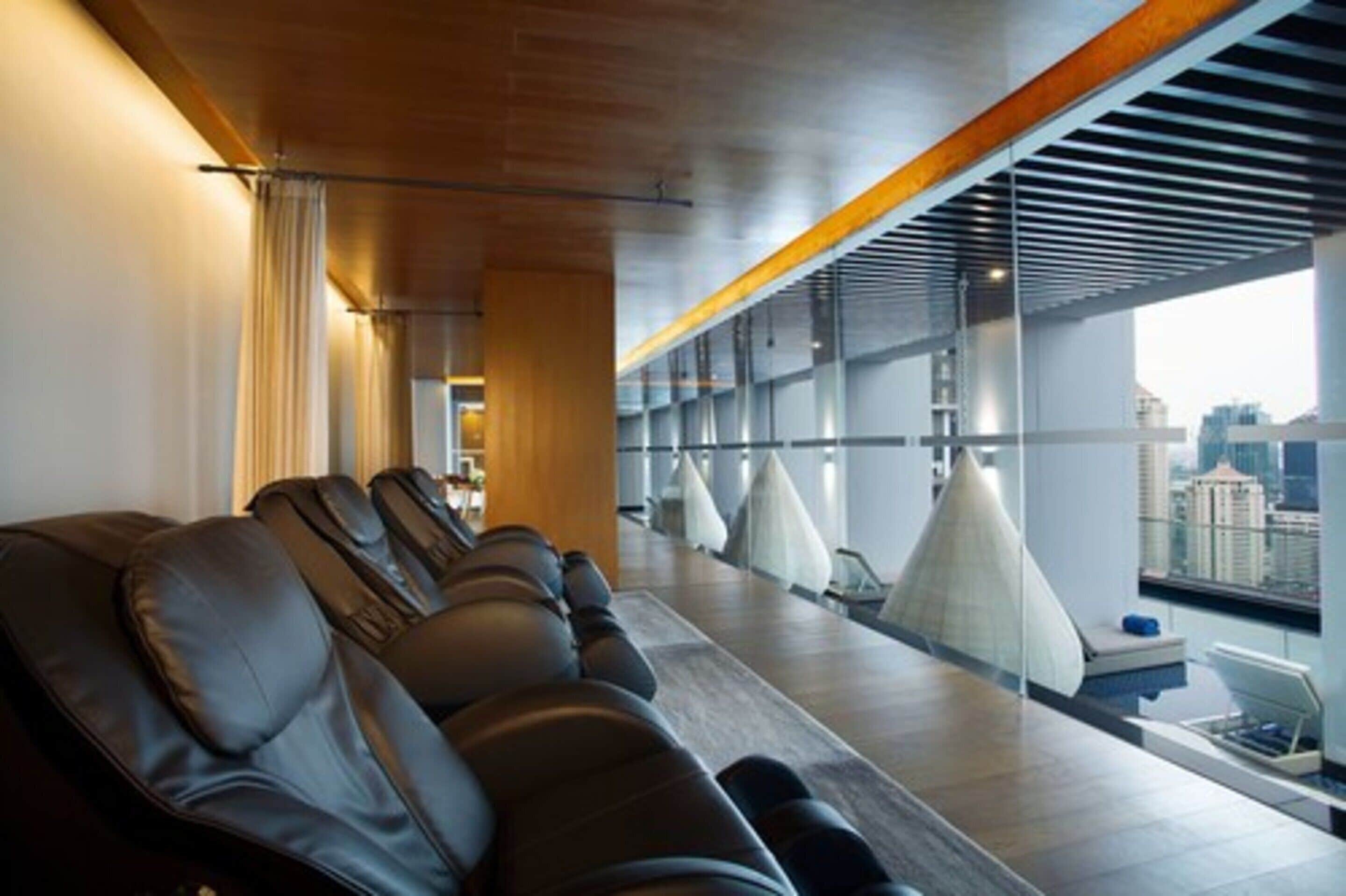 Un hall d’hôtel moderne, doté de sièges en cuir, d’un long comptoir d’accueil et de grandes fenêtres offrant une vue sur la ville.