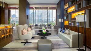 A modern lobby with a seating area, a bar, and large windows offering a city view. - Ascott Sudirman Jakarta (Jakarta)