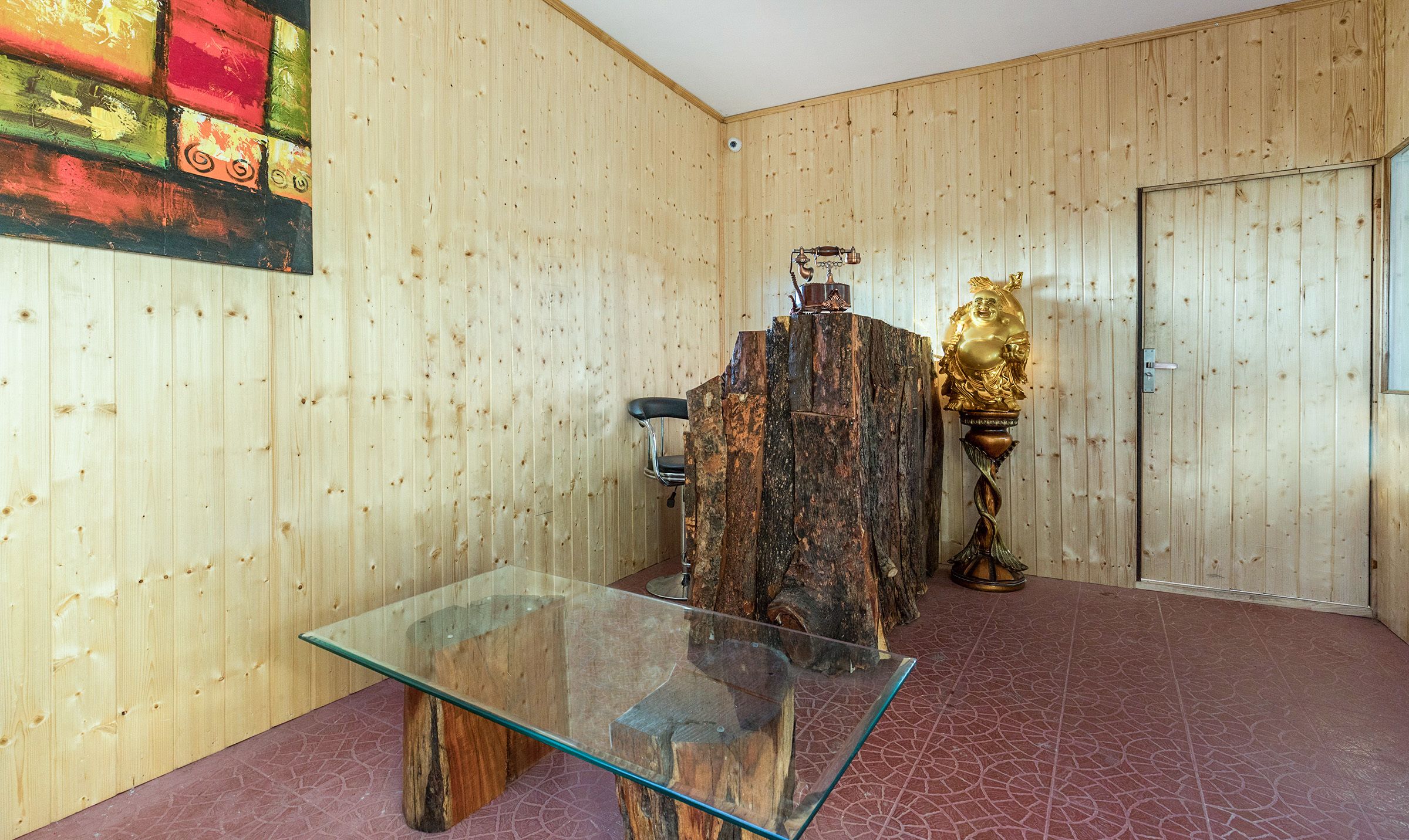 A room with wooden panel walls, a glass table, a chair, and a decorative golden statue.