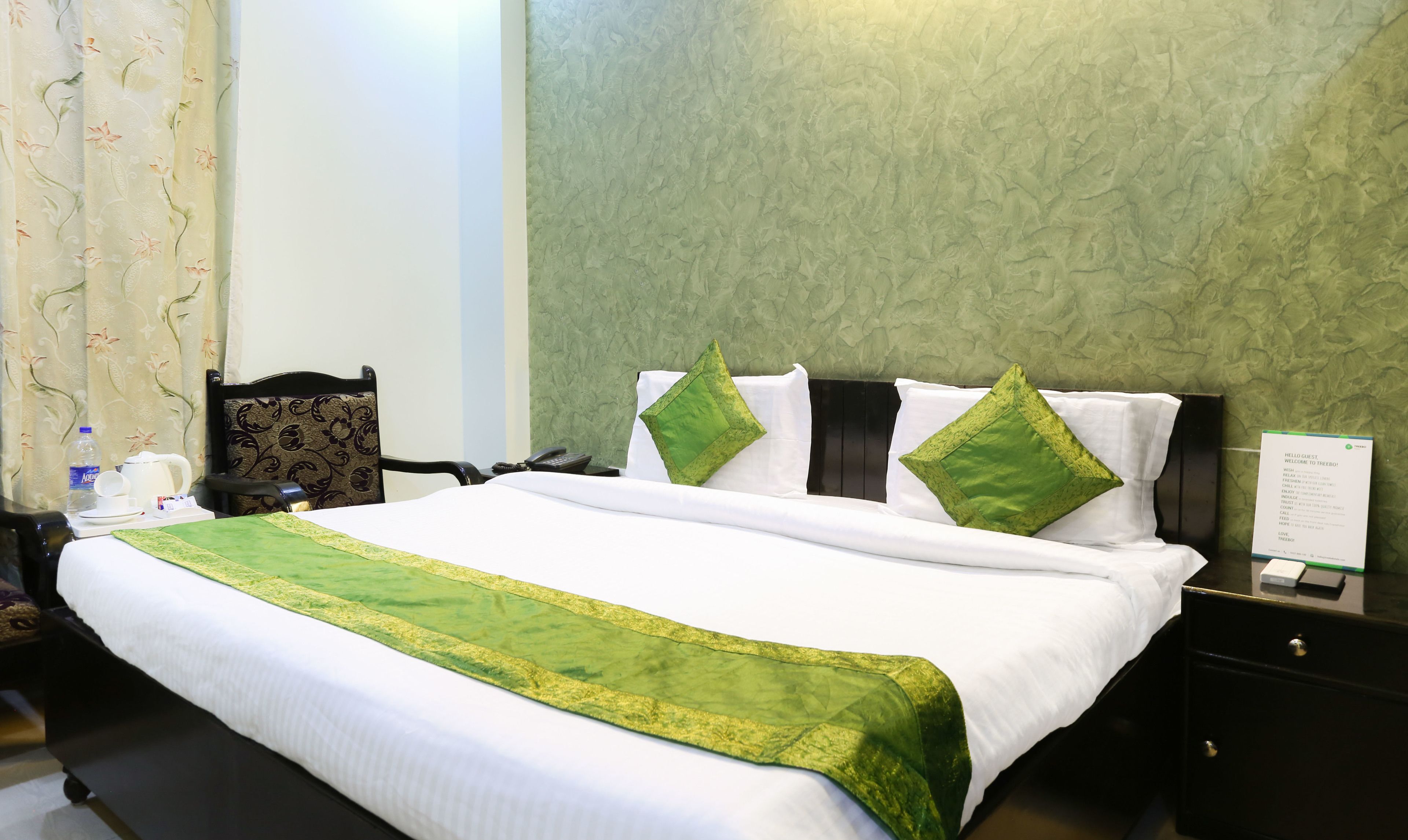 Una habitación de hotel con una cama bien hecha, una silla, una mesita de noche y una pared con un diseño texturizado.
