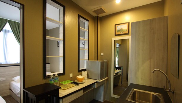 A compact hotel bathroom with a sink, mirror, and a small countertop with toiletries. - Shamrock Greenhill (Ipoh)
