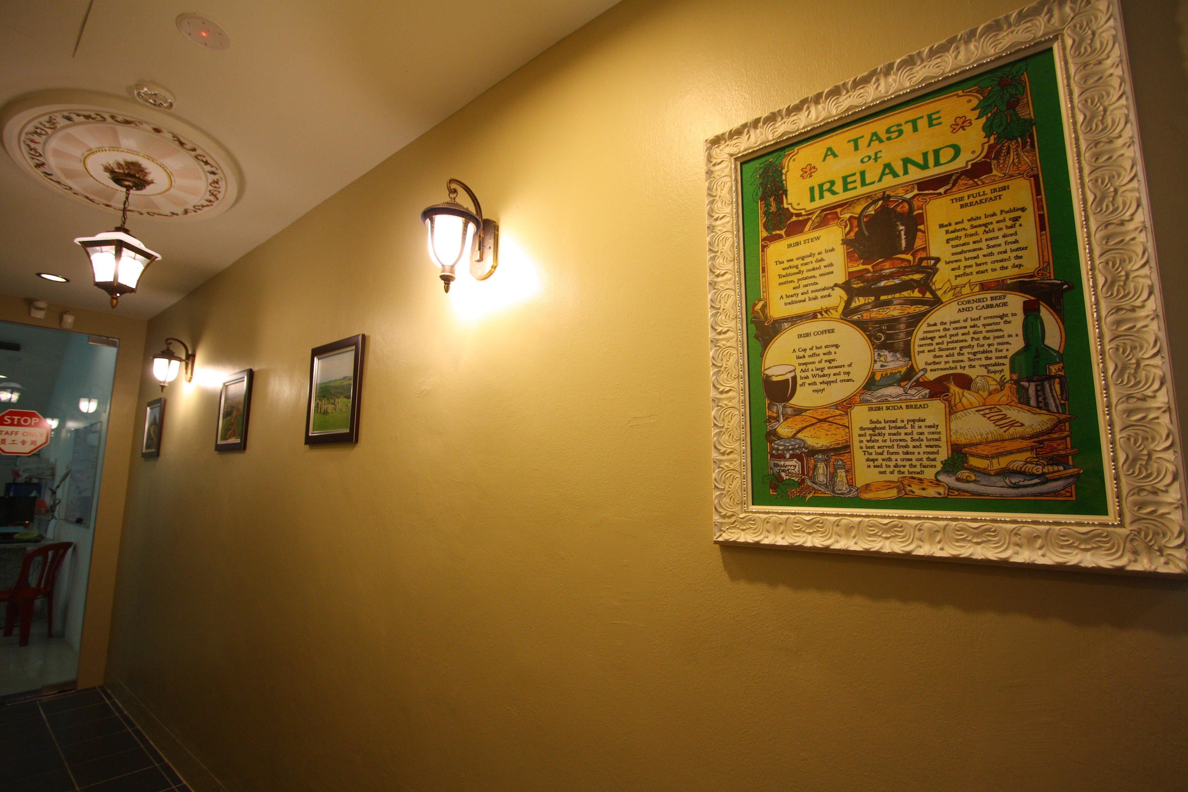A hallway with framed posters on the wall, a stop sign, and a light fixture.