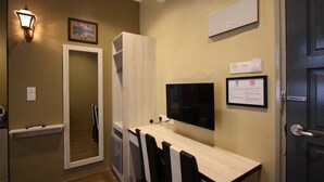 A hotel room with a wooden table, black and white chairs, a flat-screen TV, a framed picture, and a door with a handle. - Shamrock Greenhill (Ipoh)