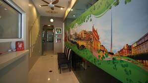 A reception area with a ceiling fan, a glass wall with a cityscape mural, and a seating area with chairs. - Shamrock Greenhill (Ipoh)
