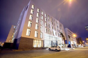 Ein modernes Hotel mit markantem Eingang, mehreren Etagen und einer gut beleuchteten Fassade.