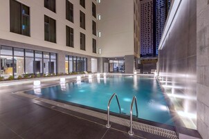 Una piscina interior con agua cristalina, rodeada por un edificio moderno con amplios ventanales y suelo de baldosas.