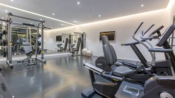 A modern gym with various exercise equipment, including a treadmill, weight machines, and a mirrored wall.