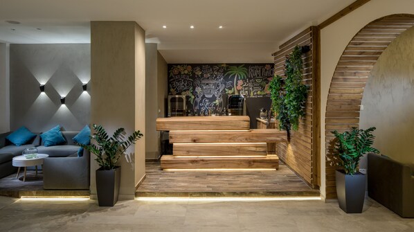 A modern interior with a staircase, a sofa, and potted plants.