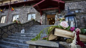 Un edificio de piedra con una escalera de madera que conduce a una entrada con techo rojo.