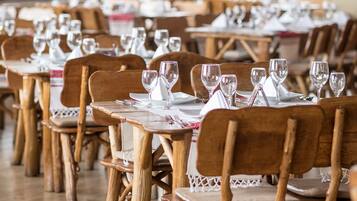 A restaurant with wooden tables and chairs, arranged in rows.