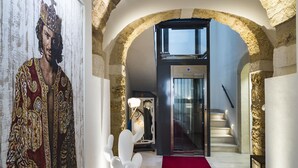A hallway with a red carpet, a glass elevator, and a staircase. - Re Federico Boutique Hotel (Syracuse)