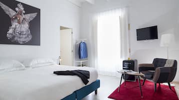 Een hotelkamer met een groot bed, een televisie, een bureau met stoel, een rood kleed en een garderobe.