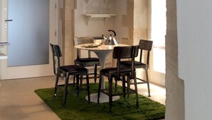 A modern dining area with a round table, four chairs, a black pendant light, and a small green rug. - Re Federico Boutique Hotel (Syracuse)