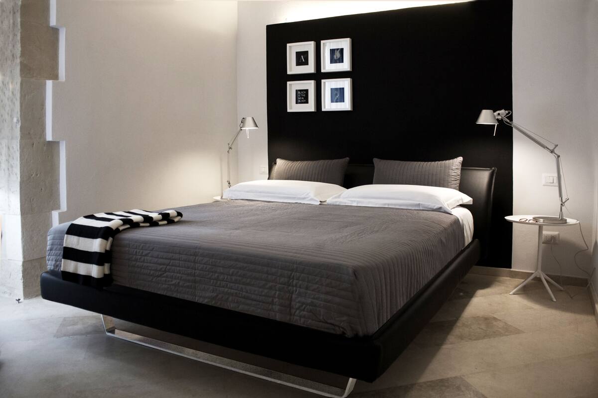 A modern bedroom with a bed, bedside tables, and a headboard with framed pictures.