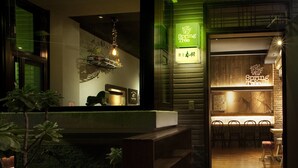 A cozy interior with a bar area, wooden shelves, and a green-lit sign. - SpringTree B&B (Dongshan)