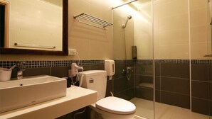 A modern bathroom with a large mirror, a sink, a toilet, and a glass-enclosed shower. - SpringTree B&B (Dongshan)