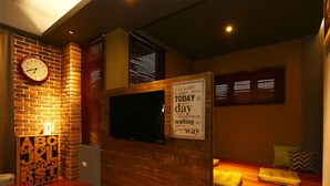 A cozy room with a brick wall, a clock, a television, and a motivational sign. - SpringTree B&B (Dongshan)