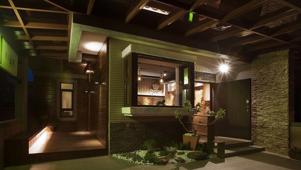 A modern building with a stone facade, a wooden deck, and a well-lit entrance. - SpringTree B&B (Dongshan)