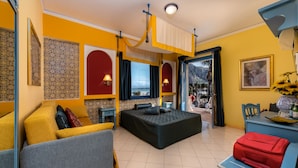 A room with a bed, a sofa, a desk, and a view of the outdoors. - Hotel Ristorante Mediterraneo Faro (San Vito Lo Capo)