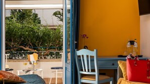 A room with a bed, a desk, a chair, a table, and a window overlooking greenery. - Hotel Ristorante Mediterraneo Faro (San Vito Lo Capo)