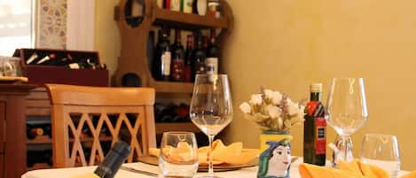 A dining table set with wine glasses, a bottle of wine, and a vase with flowers.