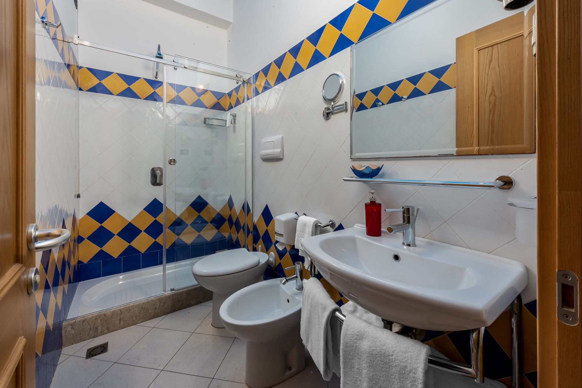 A bathroom with a shower, toilet, bidet, and sink.