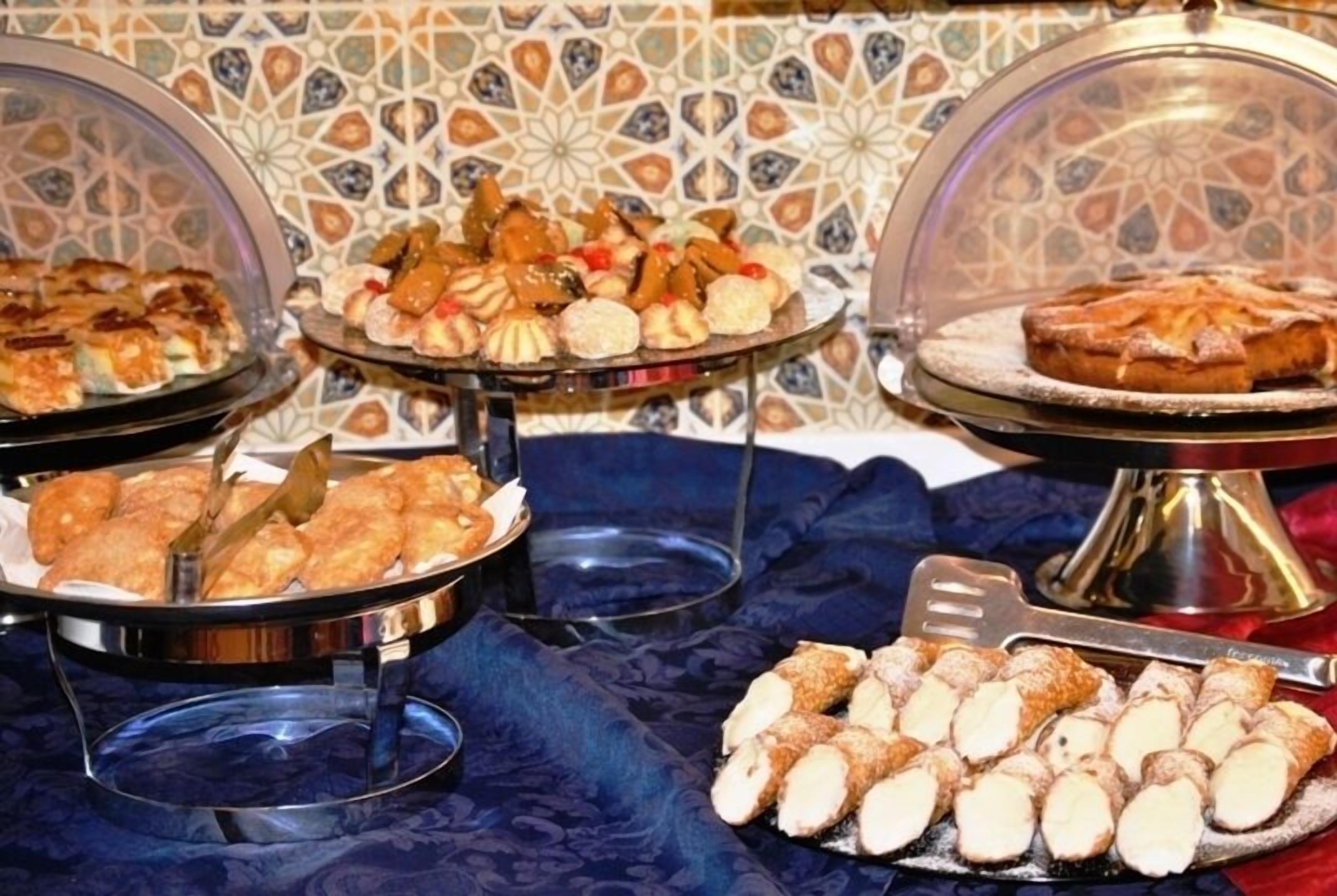 A buffet with various pastries and desserts displayed on glass stands.