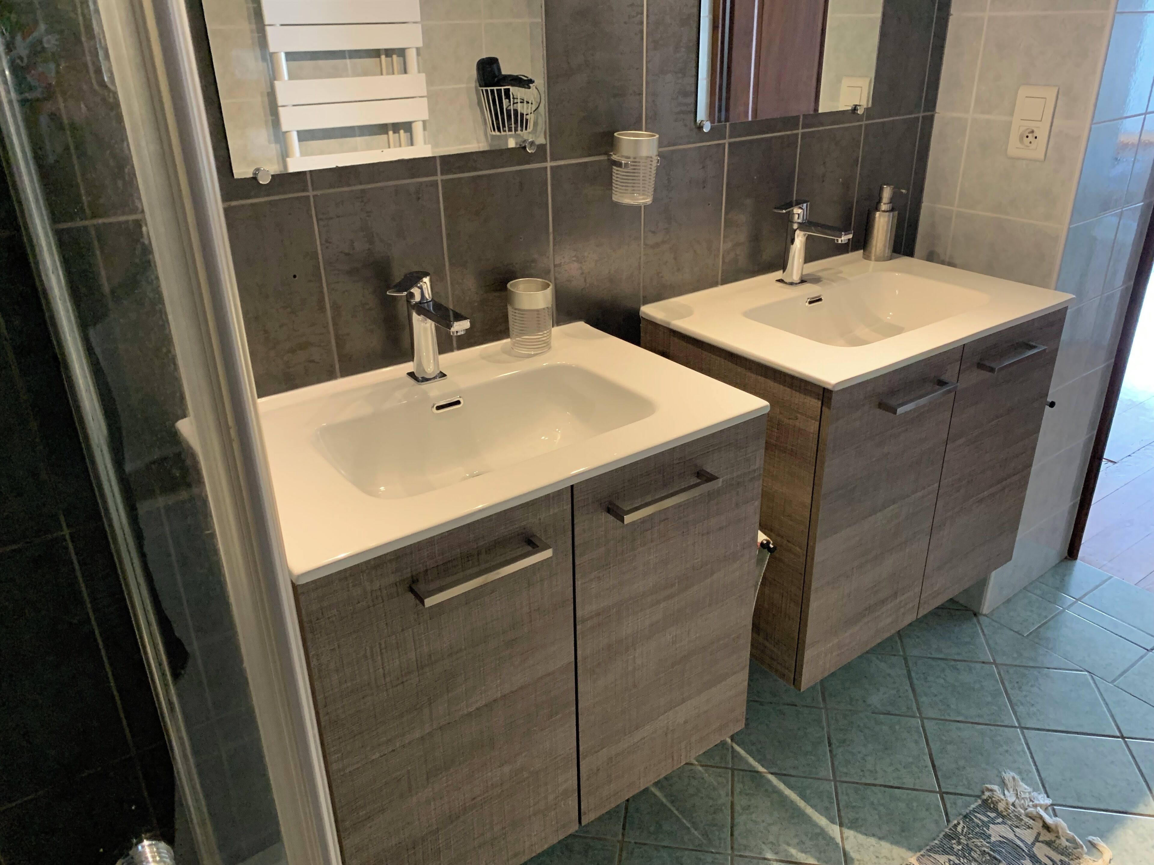 A modern bathroom with two sinks, a mirror, and a towel rack.