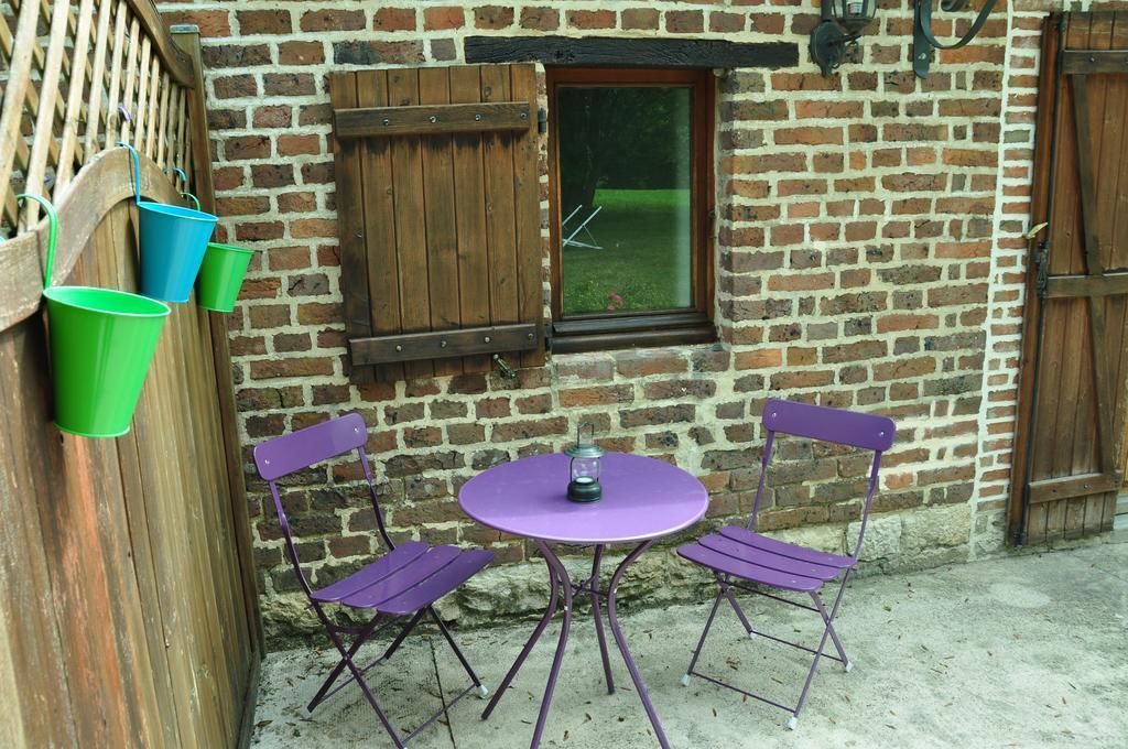 Un bâtiment en briques avec une fenêtre, une porte et une table entourée de chaises.