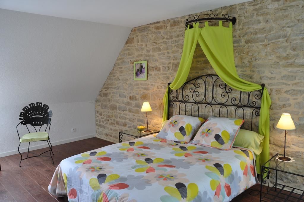 A bedroom with a bed, a chair, and a stone wall.