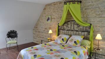 A bedroom with a bed, a chair, and a stone wall.