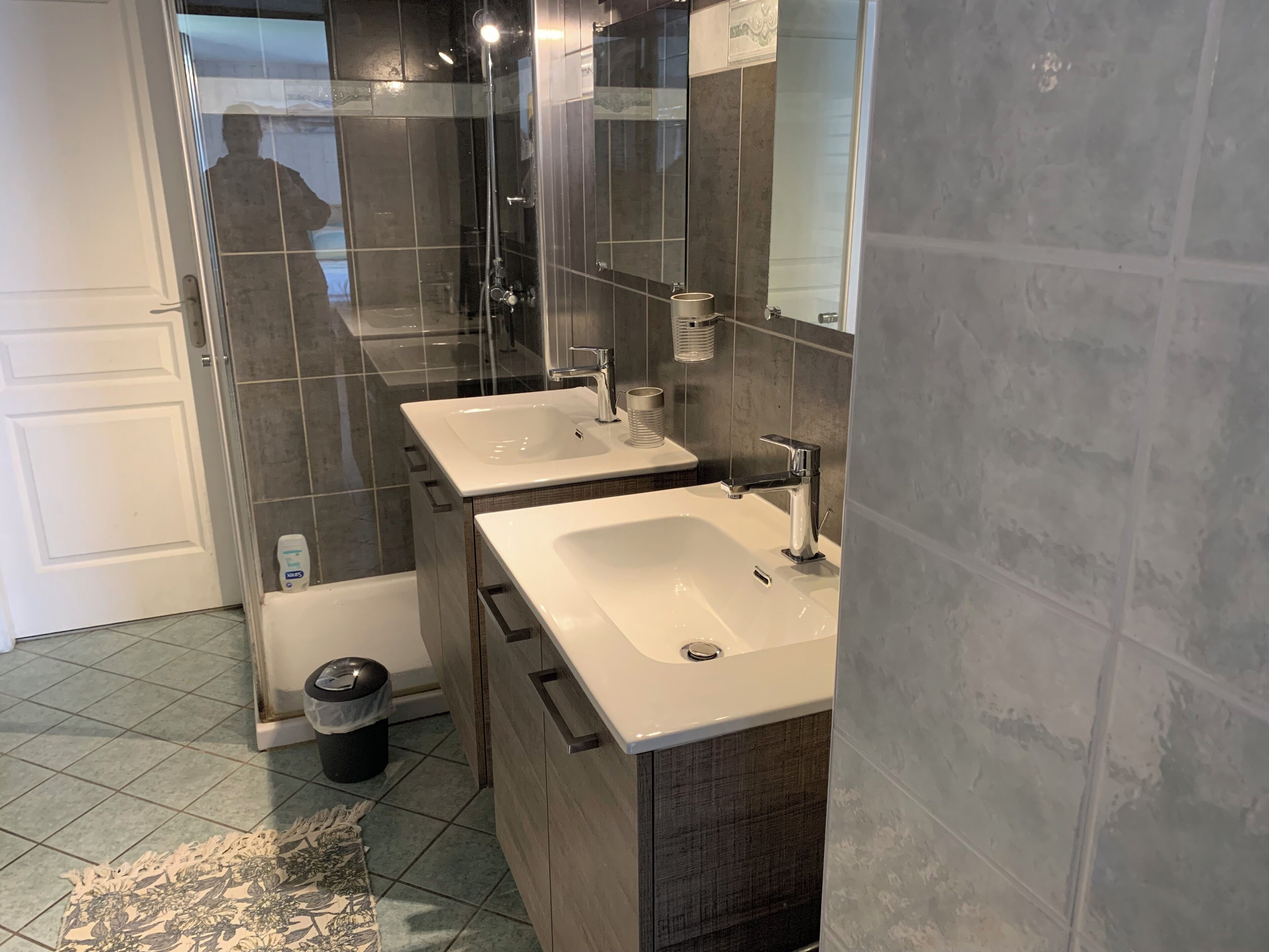 A modern bathroom with two sinks, a shower, and a toilet.