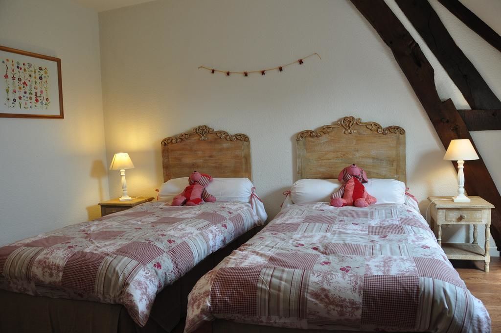 Een kamer met twee bedden, elk met een houten hoofdbord en een bedspreide met bloemenprint. Er staan nachtlampjes op houten nachtkastjes.