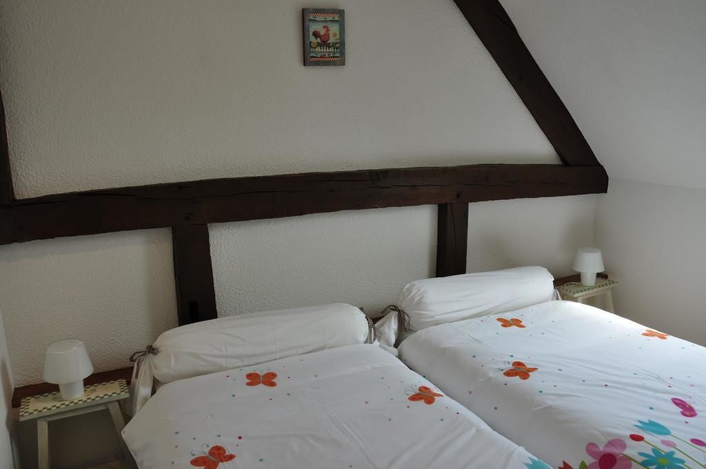 Una camera da letto con due letti, un trave in legno al soffitto, un tavolino con una lampada e un quadro appeso al muro.