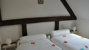 Una camera da letto con due letti, un trave in legno al soffitto, un tavolino con una lampada e un quadro appeso al muro.