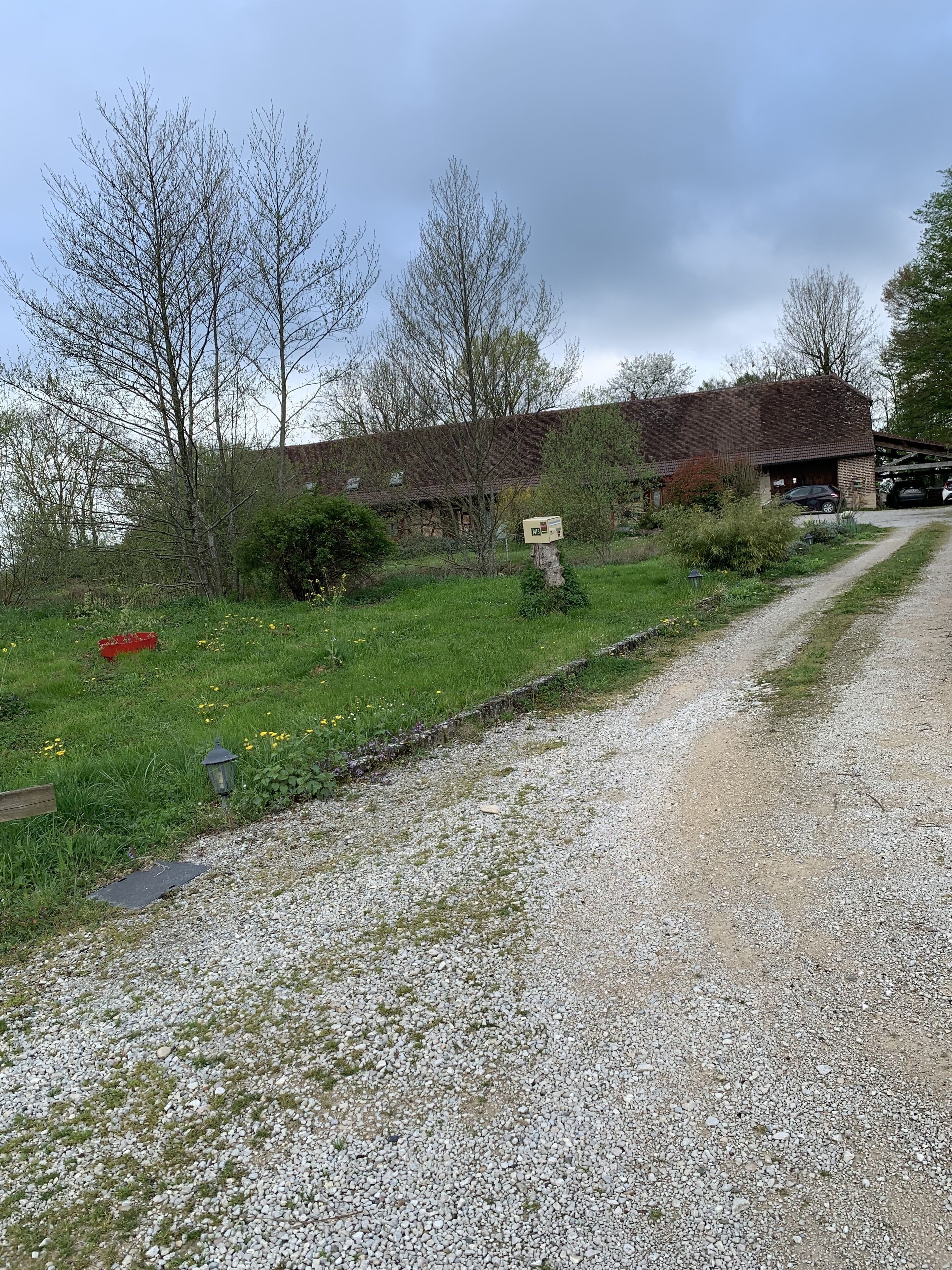 A gravel path leading to a rustic building with a brick exterior and a garage.