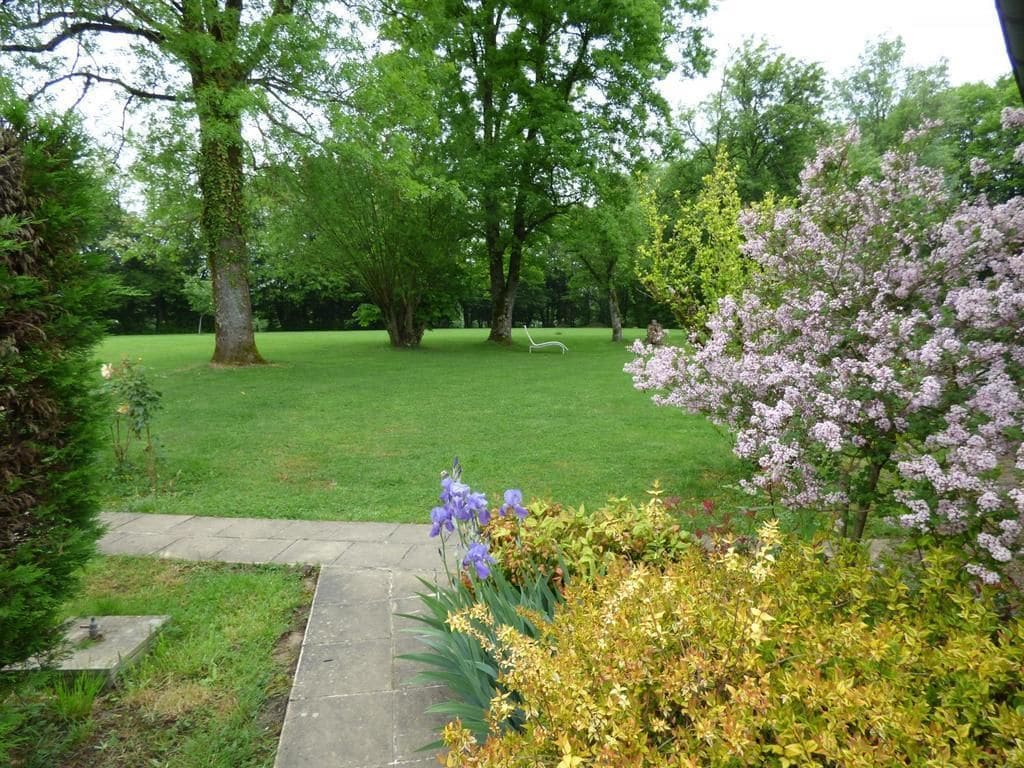 Un jardín cuidado con césped, árboles y plantas con flores.