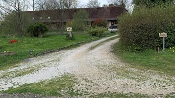 Un sendero de grava que conduce a un edificio con un cartel que dice "Ferme d'Aristide".