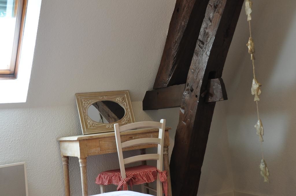 A rustic room with a wooden chair, a small table, and a mirror with a decorative frame.