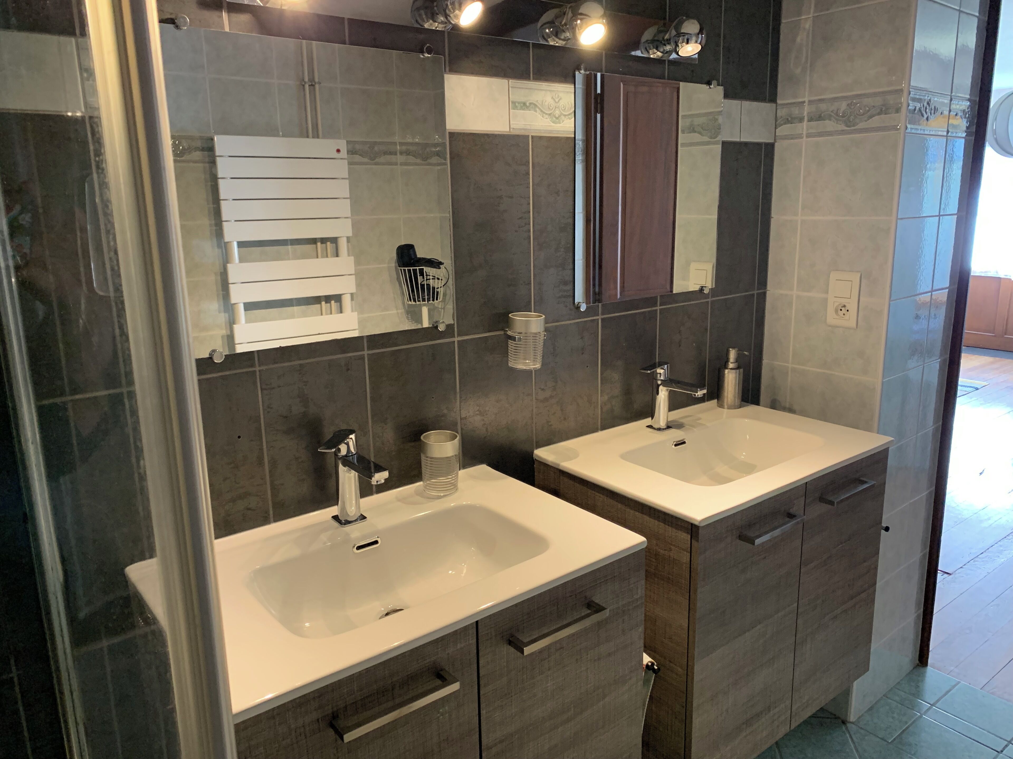 Une salle de bain moderne avec deux lavabos, un miroir et un espace douche.