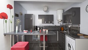 Une cuisine moderne dotée d’un îlot central, d’un lave-linge et d’un évier.
