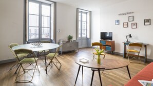Un salon moderne comprenant une table à manger, des chaises, un téléviseur et un canapé.